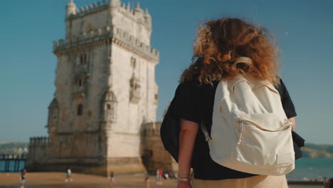 woman with backpack viewing the belem tower in portugal