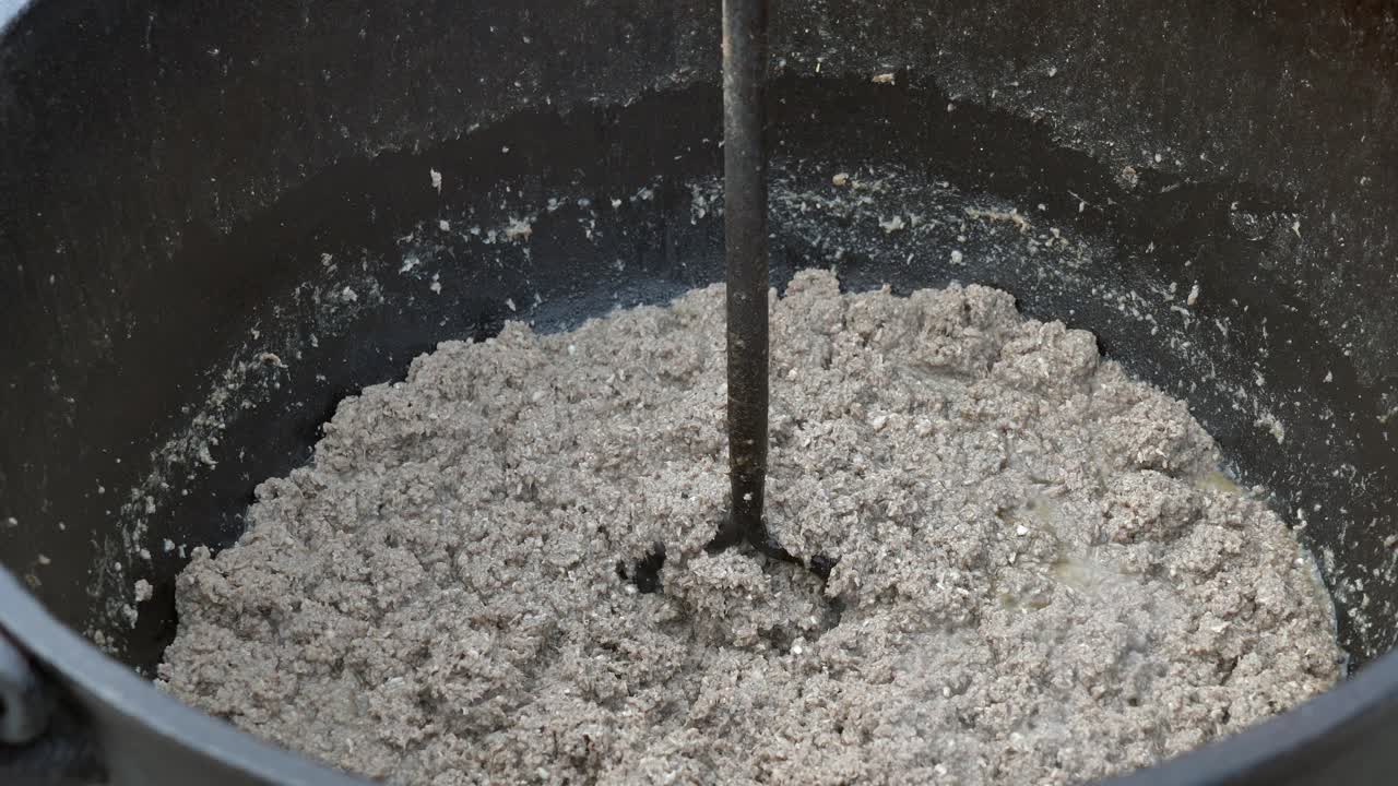 перемешивание молотого мяса или путтинов в железном котелке на дровяном огне