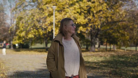 caucasian senior woman walking alone at the park in autumn