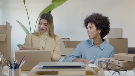 two female entrepreneurs working in office, checking inventory and giving high five