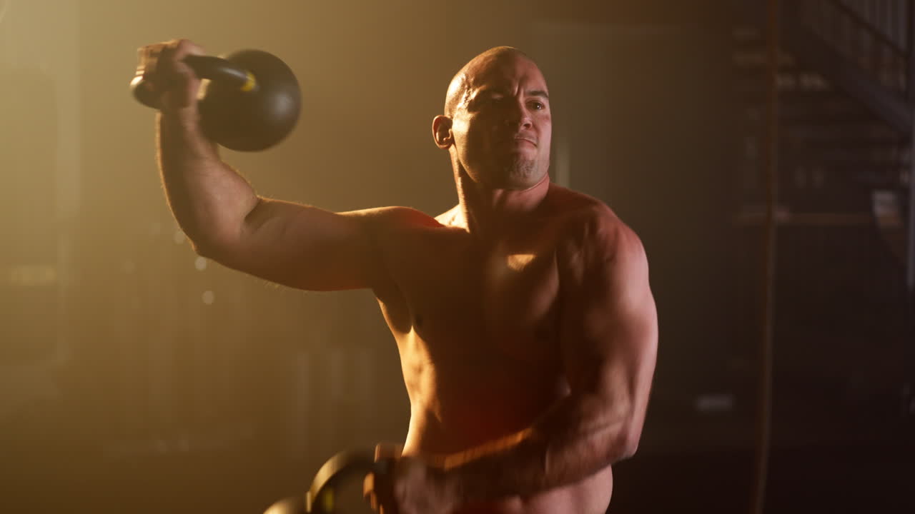 Muscular man working out with kettlebell in gym