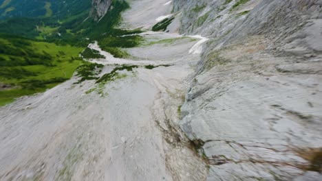 fpv drone dive down a steep gray mountain wall in austria