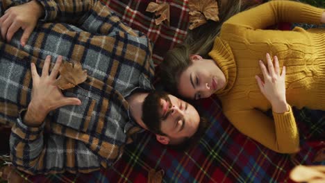 video of happy caucasian warmly dressed couple lying on blanket in the garden