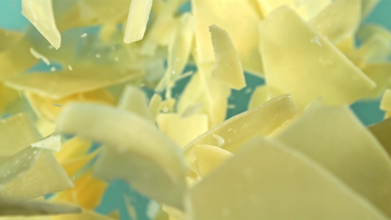 Scaglie di cioccolato bianco che cadono al rallentatore su sfondo blu