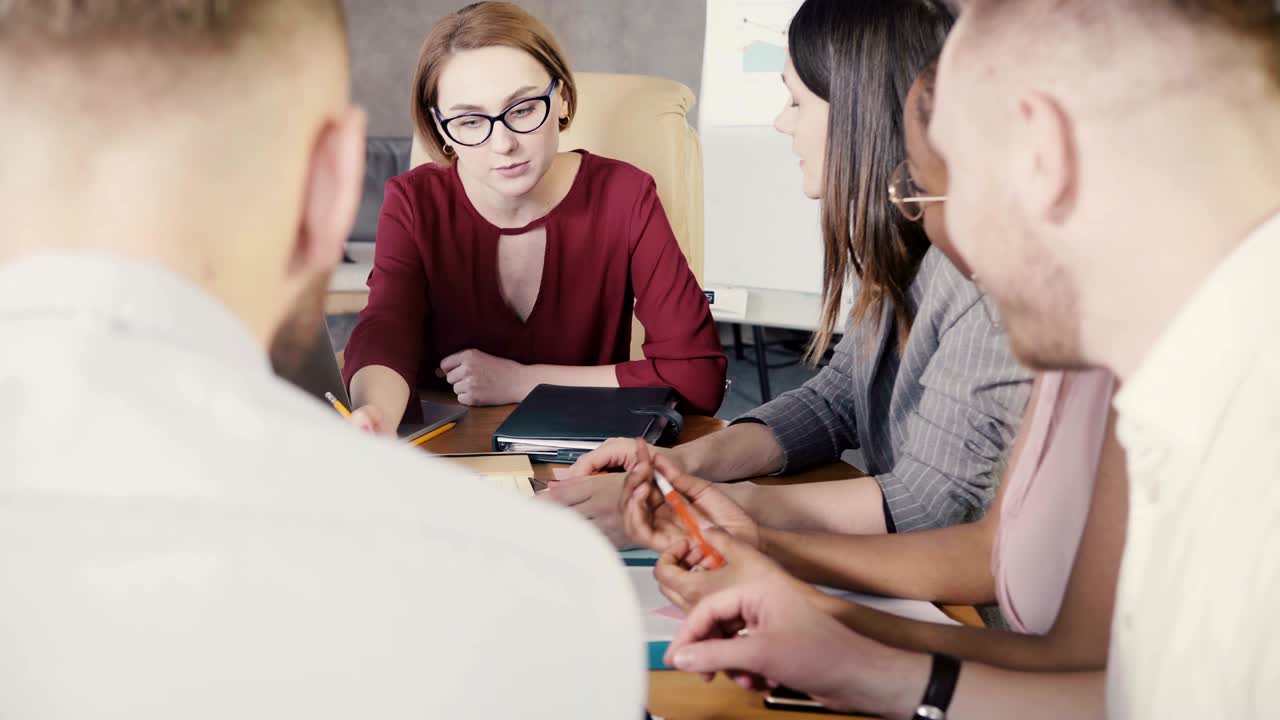 Affermata donna d'affari che conduce una riunione d'ufficio. Felice gruppo multirazziale che lavora a una partnership strategica di marketing. 4K