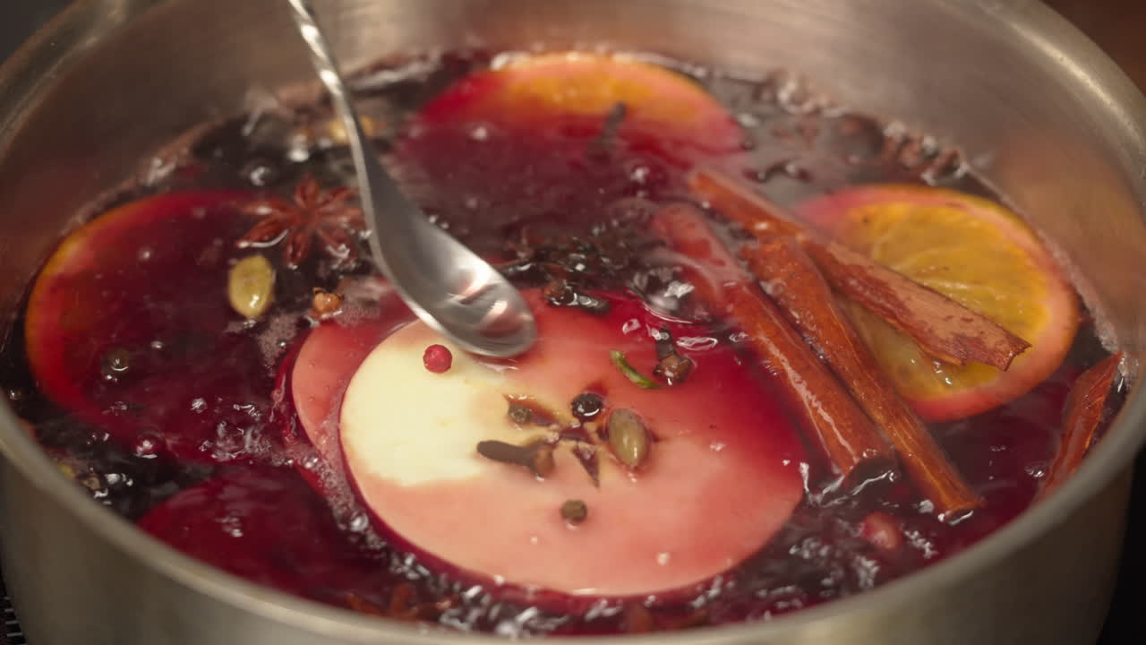 Preparando vinho quente com especiarias, fatias de laranja e maçã.