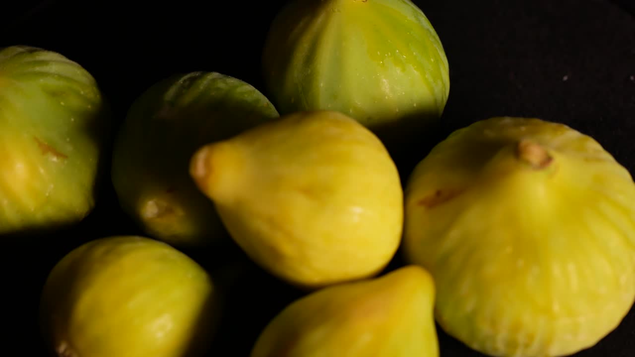 una foto de unos higos girando sobre una superficie negra