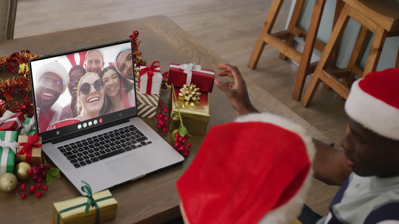 pareja diversa con sombreros de santa teniendo llamada de video portátil con amigos diversos