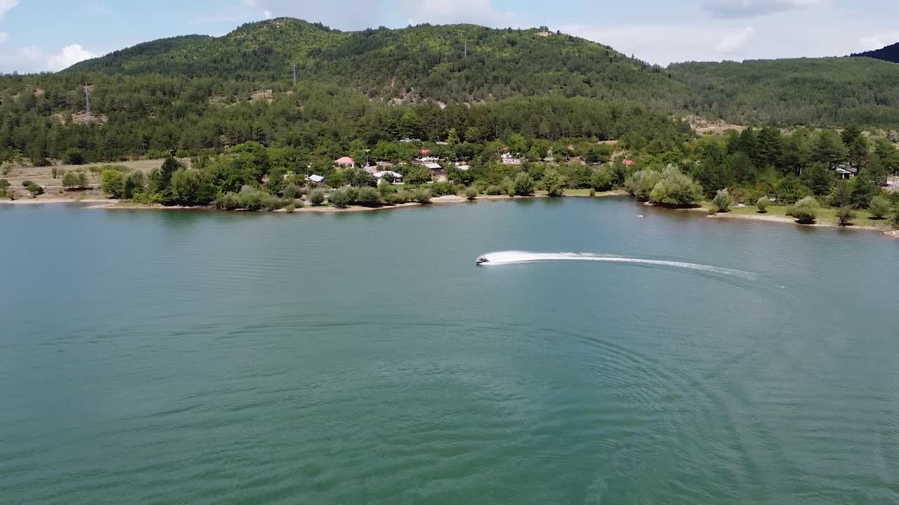 Aerial view of a jet ski on a lake surrounded by pine trees