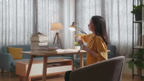 mujer estirándose en el escritorio, estudiando en casa