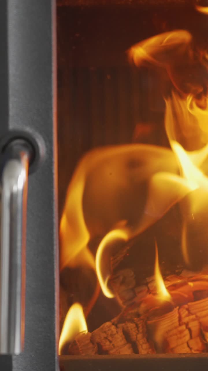 video vertical de primer plano llamas de fuego troncos en la estufa de leña en casa 3