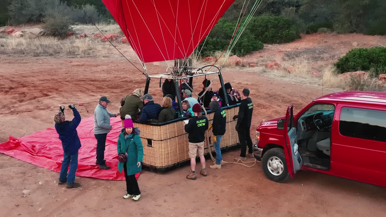 Passenger Climbs Into Wicker Basket Of Hot Air Balloon On An Early Morning In Sedona, Arizona. high angle, slowmo