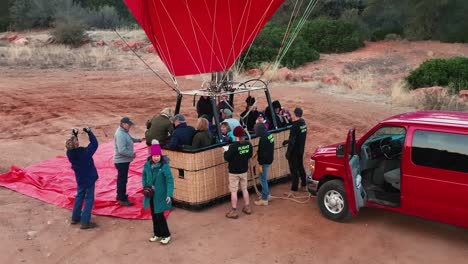 passenger climbs into wicker basket of hot air balloon on an early morning in sedona, arizona. high angle, slowmo