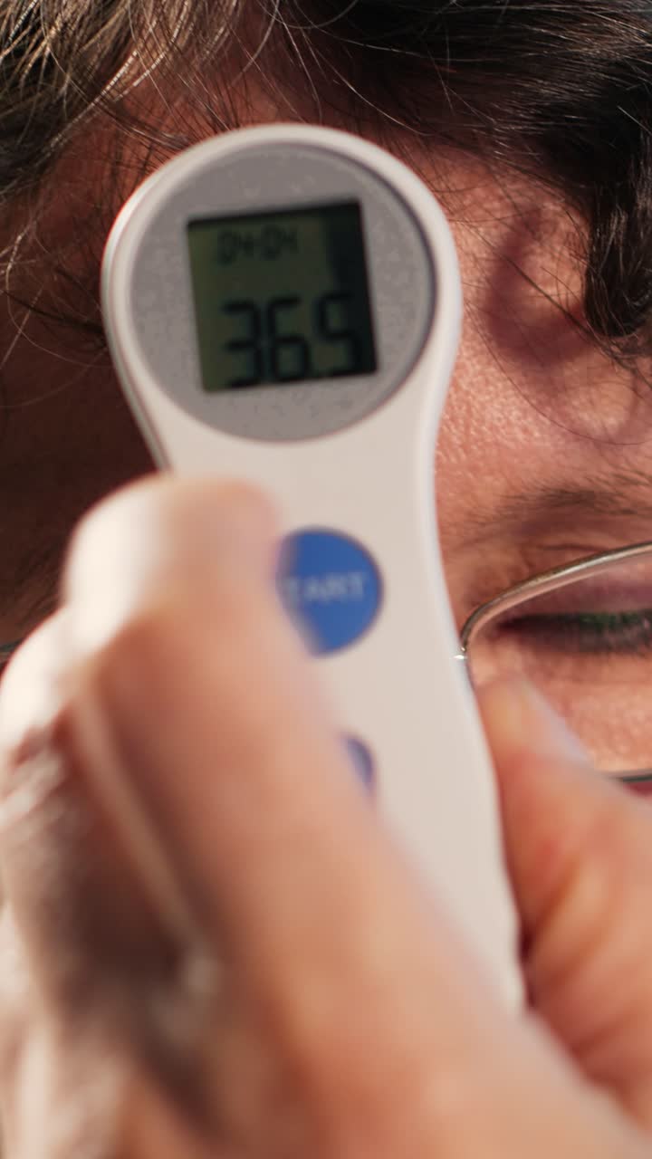 Vertical Video Male physician does fever measurements with a digital thermometer
