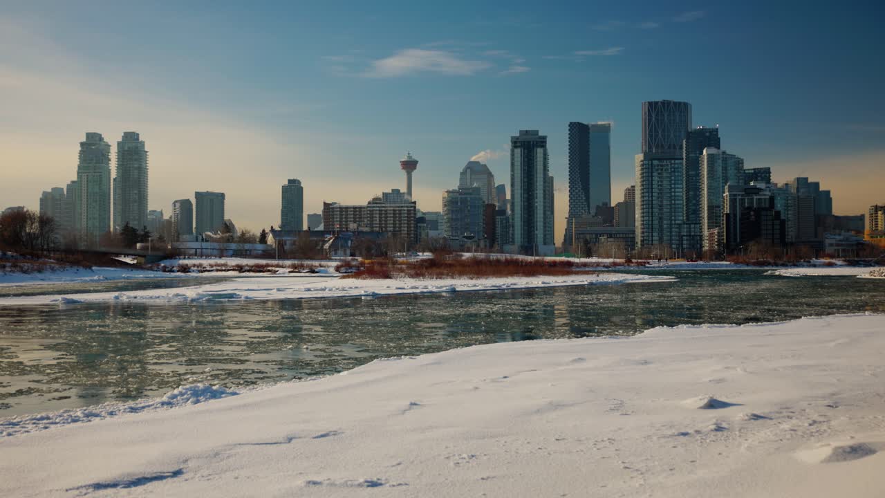 Una bellissima vista invernale diurna dello skyline del centro di Calgary in Alberta, Canada. Le torri della città e la Calgary Tower si ergono imponenti dietro il gelido fiume Bow e le rive coperte di neve fresca e luminosa