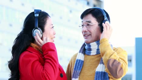 mature asian couple listening to music with headphones