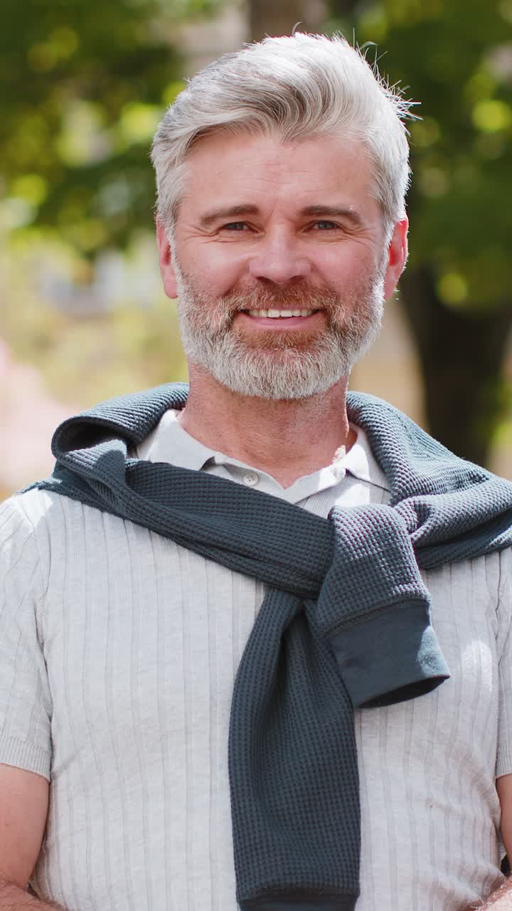 Portrett av en lykkelig, skjeggete, moden mann som smiler vennlig, glad uttrykk, ser på kameraet, avslapning