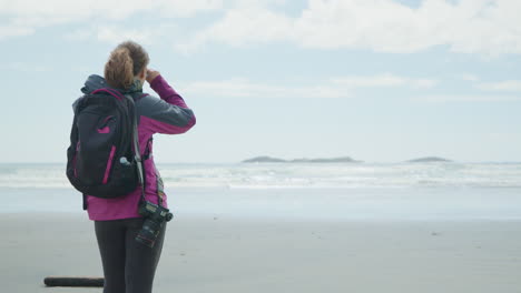 outdoor active woman with dslr camera on beach enjoys ocean view rear