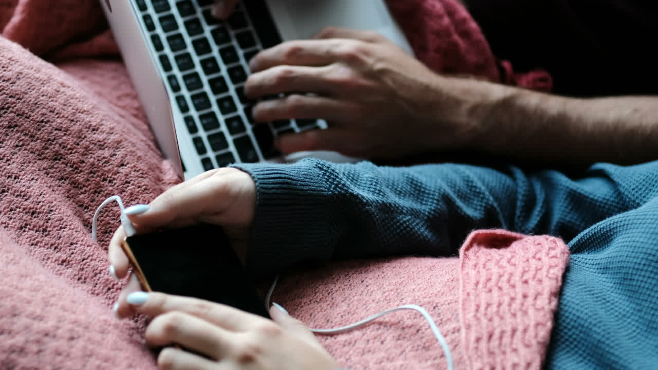 Couple using laptop and listening music on sofa 4k