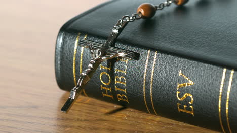 식탁 위 에 있는 성서 에 떨어지는  rosary 구슬
