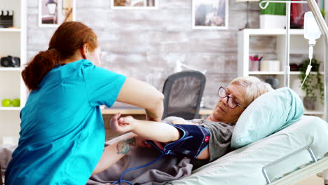 en un hogar de ancianos, una anciana tiene su presión arterial comprobada por una joven enfermera caucásica.