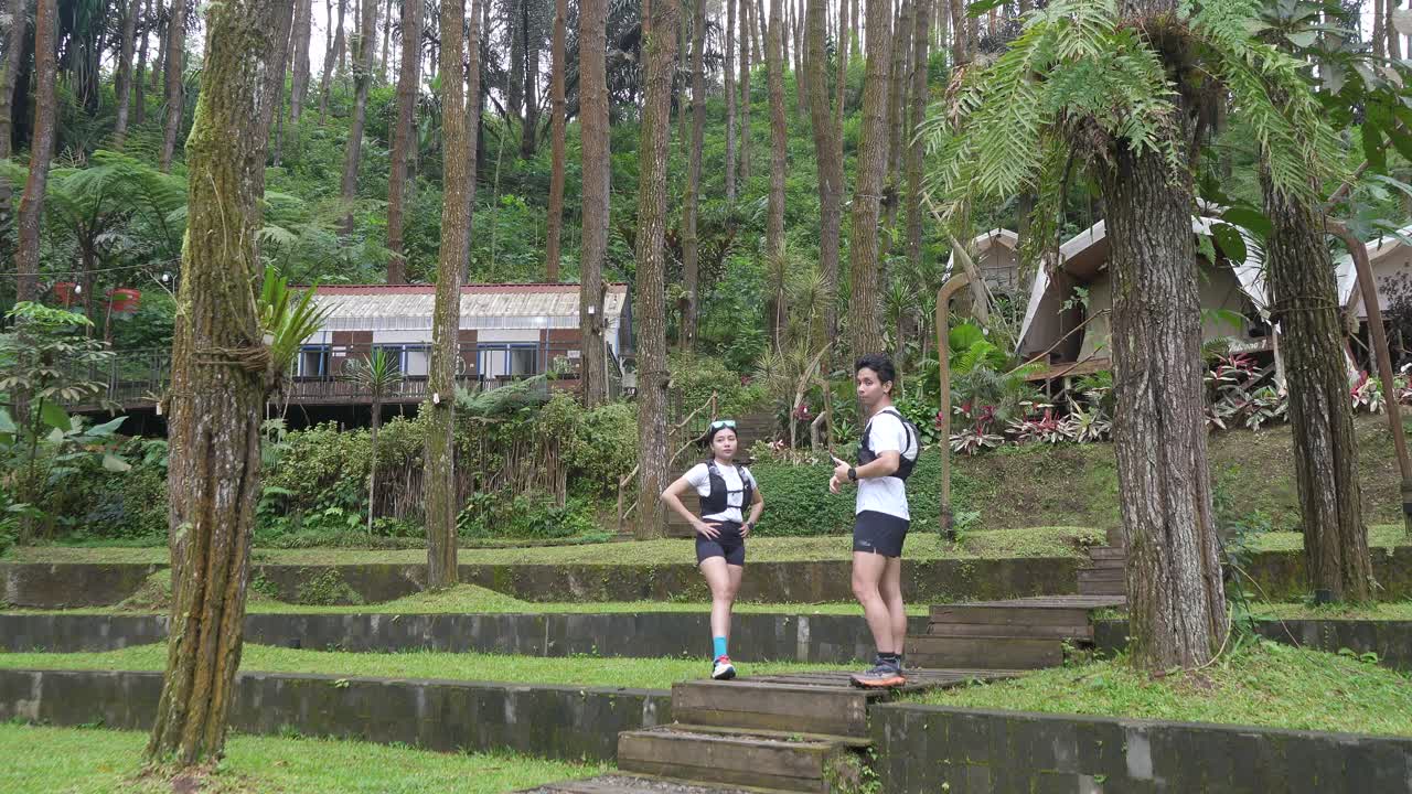 Asian couple resting and talking during outdoor workout in forest trail
