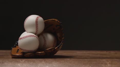 close up studio baseball still life with balls in catchers mitt on wooden floor 2