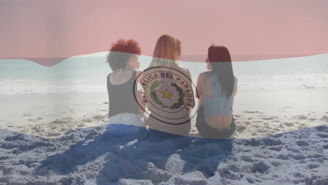 paraguay flag animation over three women sitting on beach facing ocean