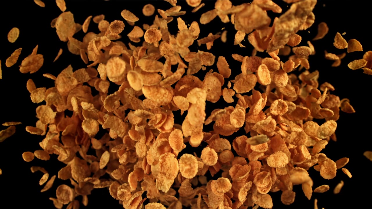 Crispy Golden Cornflakes Floating in Slow Motion on Black Background