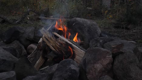 campfire shortly after being lit with pine logs surrounded by boulders