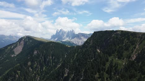 Panorama-De-Un-Hermoso-Paisaje-De-Montaña-Con-Prados-Verdes-Y-Bosques-Y-Montañas-Escarpadas-Al-Fondo,-Dolomitas,-Italia,-Europa,-Drone