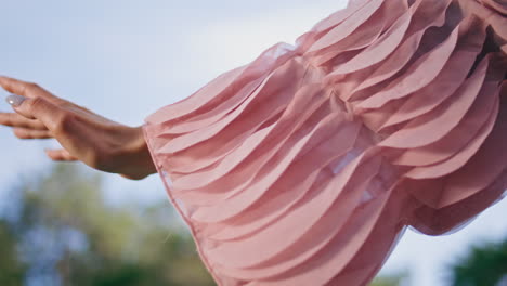 gentle woman hand raising to blue sky wearing airy stylish clothing close up.