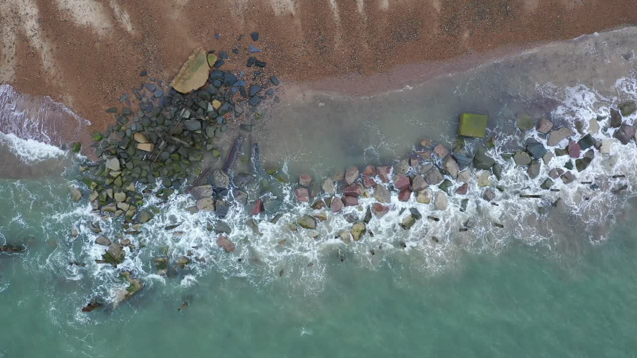 Norfolk, Happisburgh plajında gelgit çizgisi ve deniz savunmaları boyunca soldan sağa hareket eden havadan görüntü.