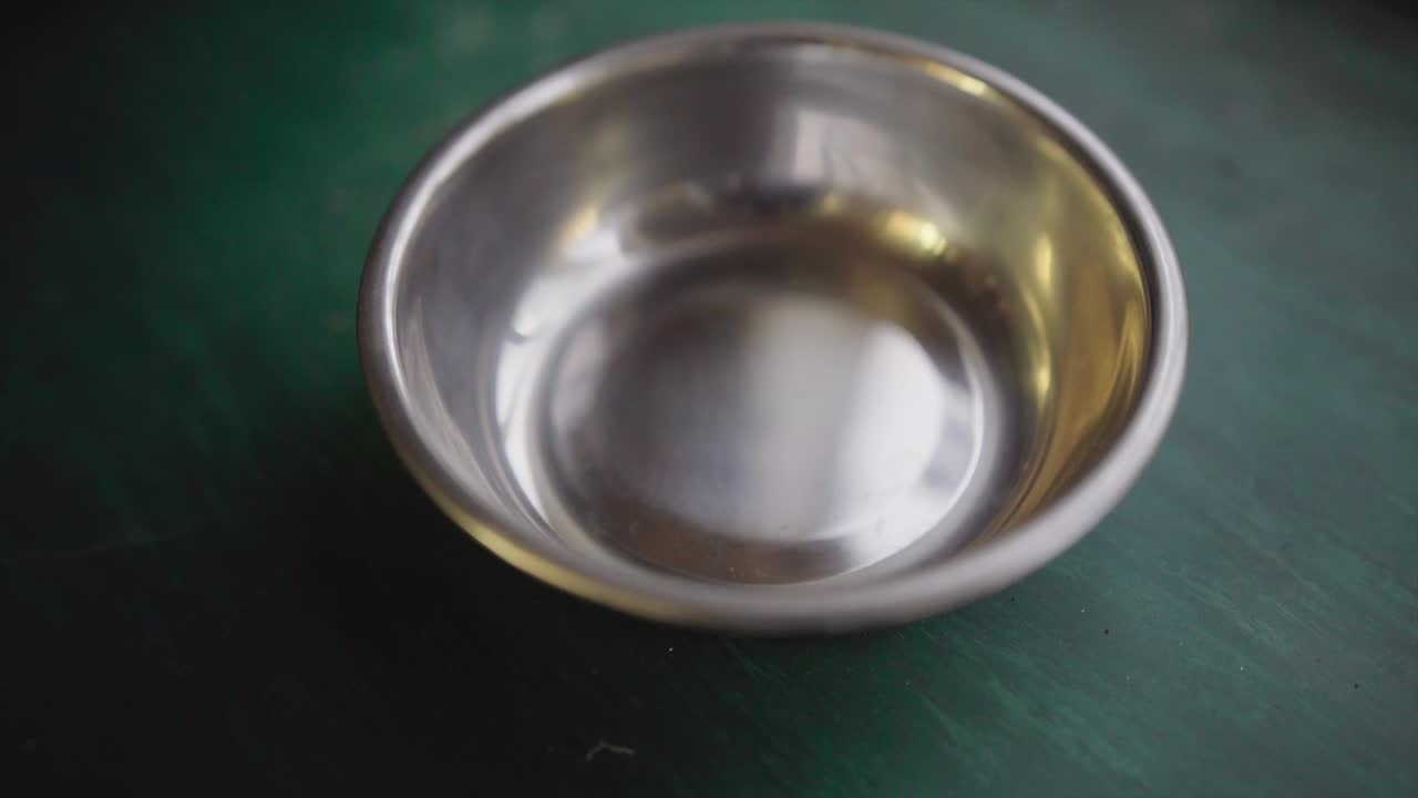 cuenca de acero inoxidable en el banco de trabajo verde.mp4