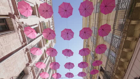 walking under pink umbrellas view from underneath. pink october sunny day blue