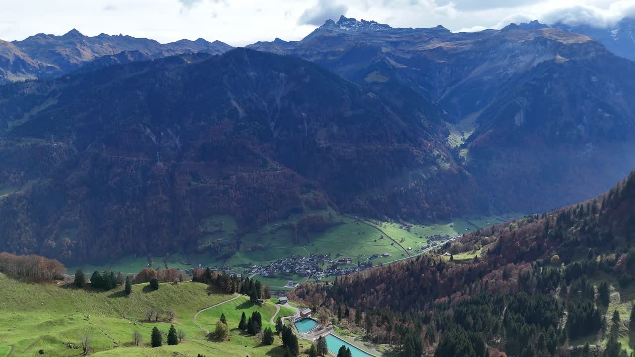 Water reservoir nestled in Swiss mountains surrounded by autumn landscape, aerial view