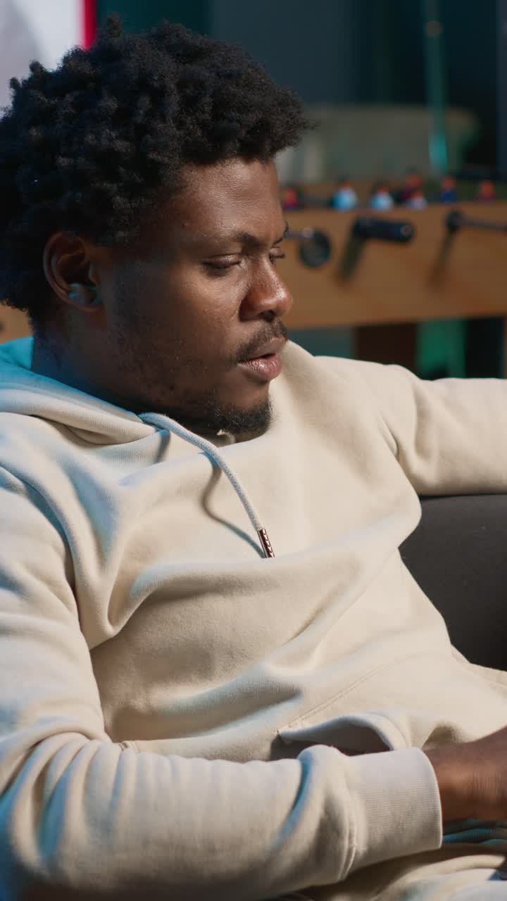 Afroamerikansk mand slapper af på sofaen og drikker af et krus