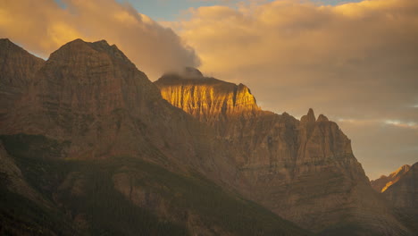 time lapse, golden sunlight on rocky mountain peaks, cliffs and clouds