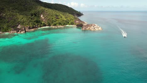 drone of anse major beach, passing speed boat from rice beach, granite stones, turquoise water, mahe seychelles 30 fps