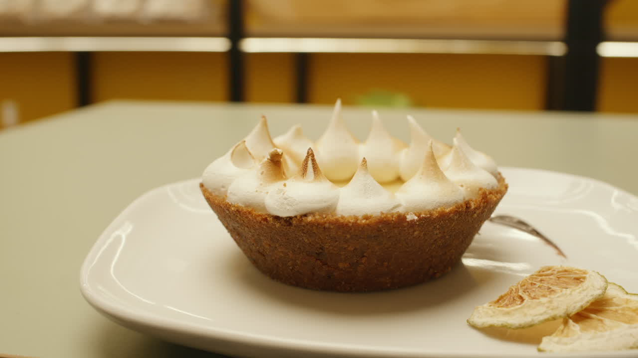 Panning shot of a lemon tart topped with meringue, highlighting its freshness, color, and creamy texture