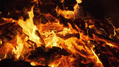 hot coals burning down a large fire and glow bright red. slow motion