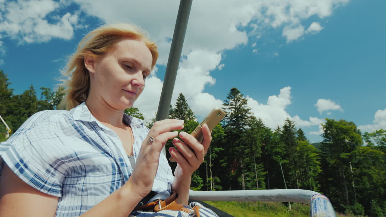 A Woman Uses A Smartphone Rides In The Open Cabin Of The Cable Car On Vacation In Connection With Th