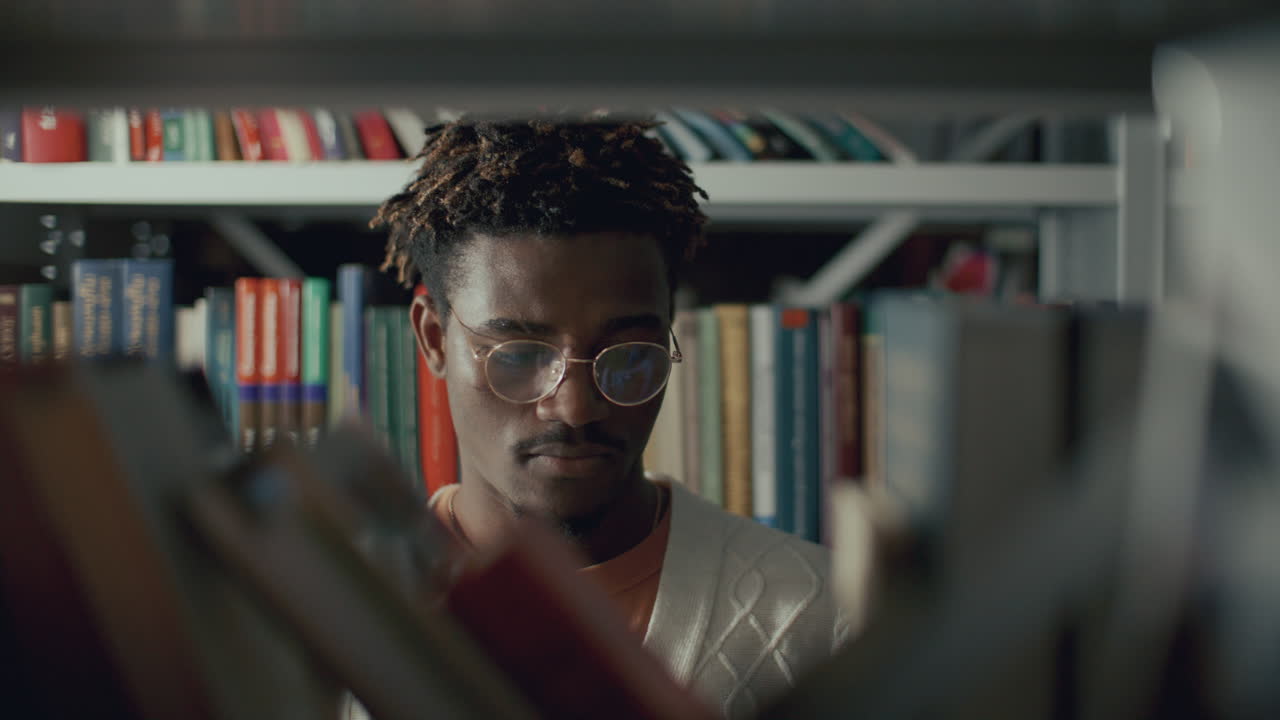 Black College Student Looking for Book on Shelf in Library