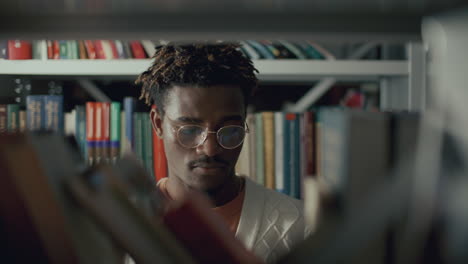 black college student looking for book on shelf in library