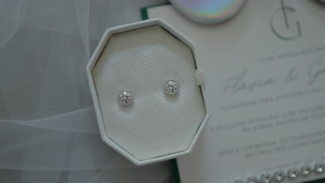 Sparkling diamond earrings in a white box with elegant wedding invitation in soft light