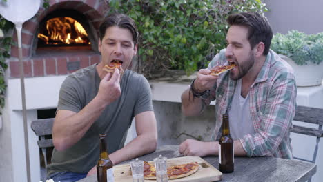 dos hombres con pizza y cervezas mientras están sentados