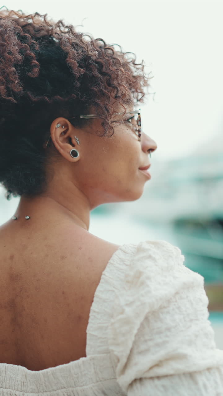 Close-up of a woman's back with curly hair, earrings, and a necklace