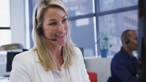 Diverse-business-people-sitting-using-computers-talking-with-phone-headsets