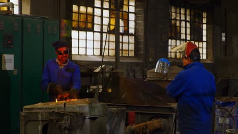 male worker mixing molted metal in furnace at workshop 4k