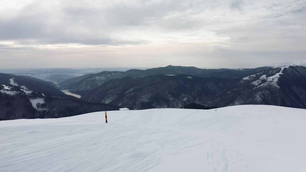 Snowy Iezer-Papusa Mountains with Rausor Dam in the distance, overcast sky